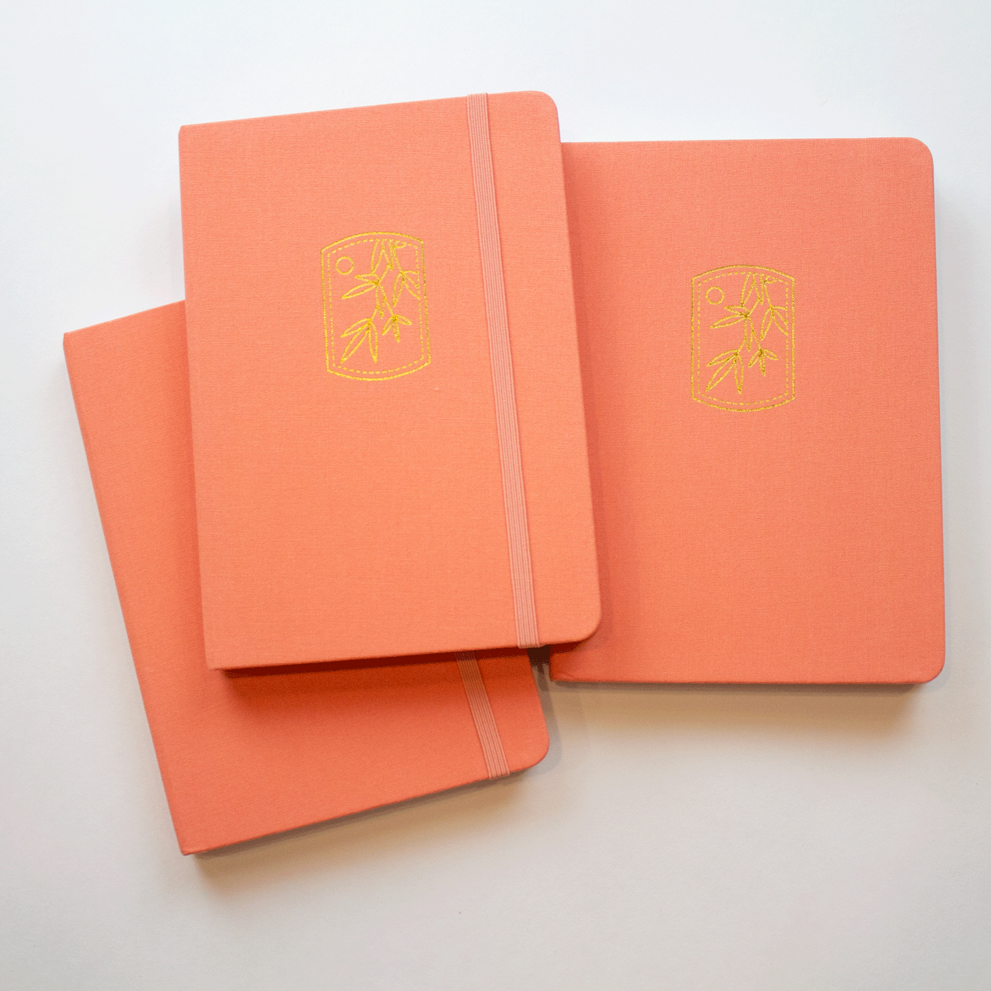 three tangerine notebooks stacked on top of each other