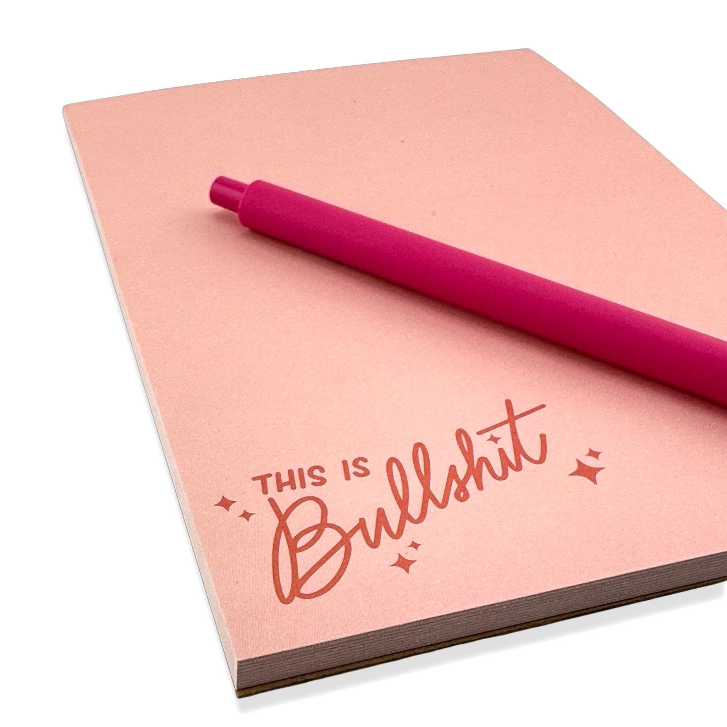 angled photo of this is bullshit notepad with a hot pink pen on top