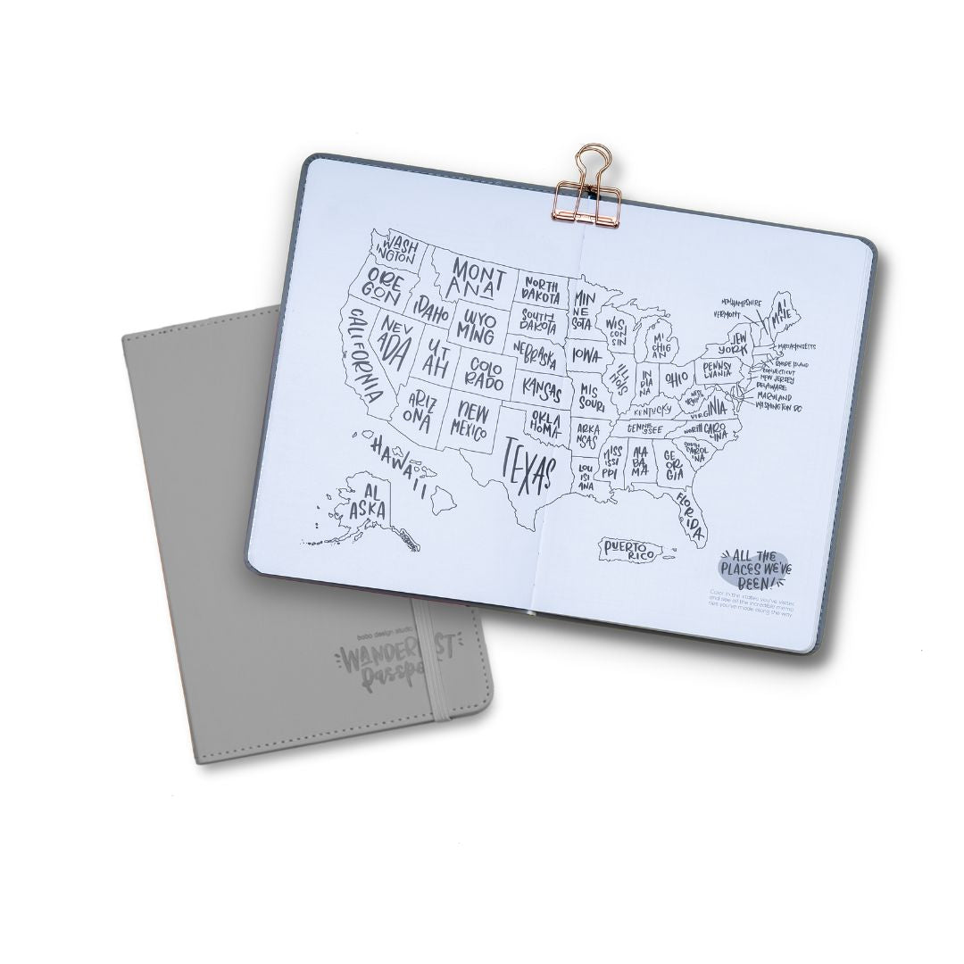 Wanderlust Passport Travel Journal A5 Notebook in gray with elastic closure, a second example book is open to the US color-in state travel map page spread (map includes continental USA, Alaska, Hawaii, and Puerto Rico)