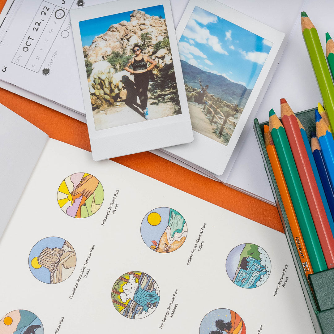 two polaroid photos on top of a small page of the national park wanderlust passport with a national parks sticker book next to it and various colored pencils