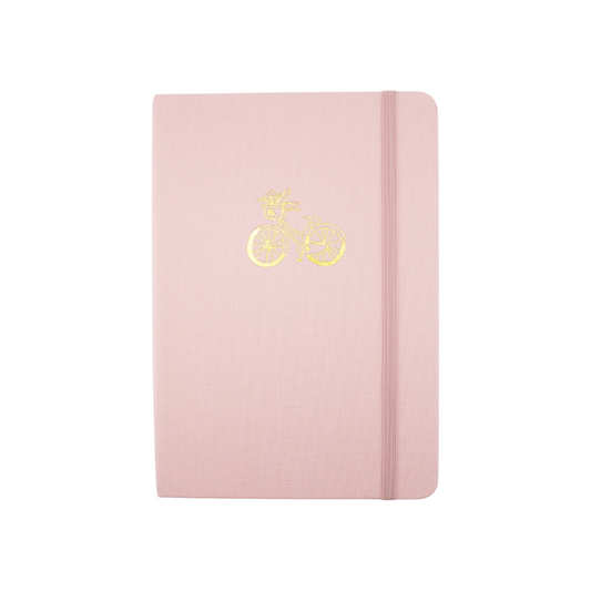 The A5 bobo Lined Journal "Bicycle" with a light pink linen cover. A gold foil cruiser bicycle with flowers in the front basket is stamped onto the center of the front cover. A corresponding light pink elastic is holding the book closed.
