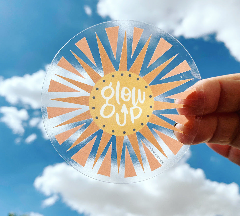 clear glow up vinyl sticker held up to the sky