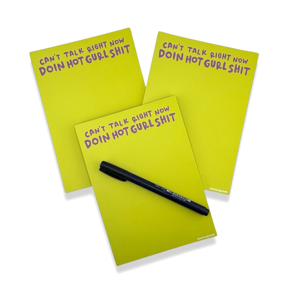 three hot gurl shit note pads stacked on one another with one pen on top