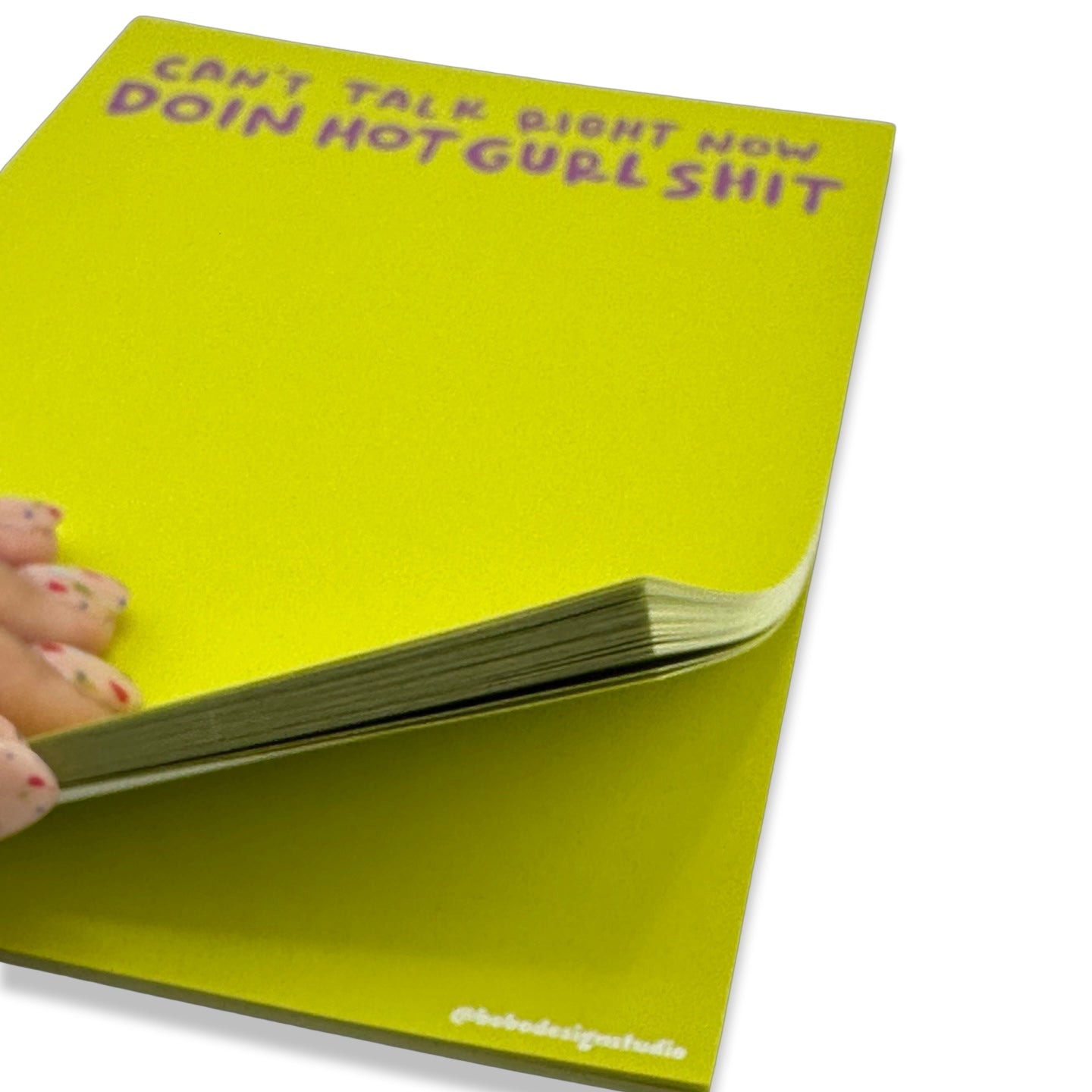 a left hand opening the bottom of the hot gurl shit notepad 