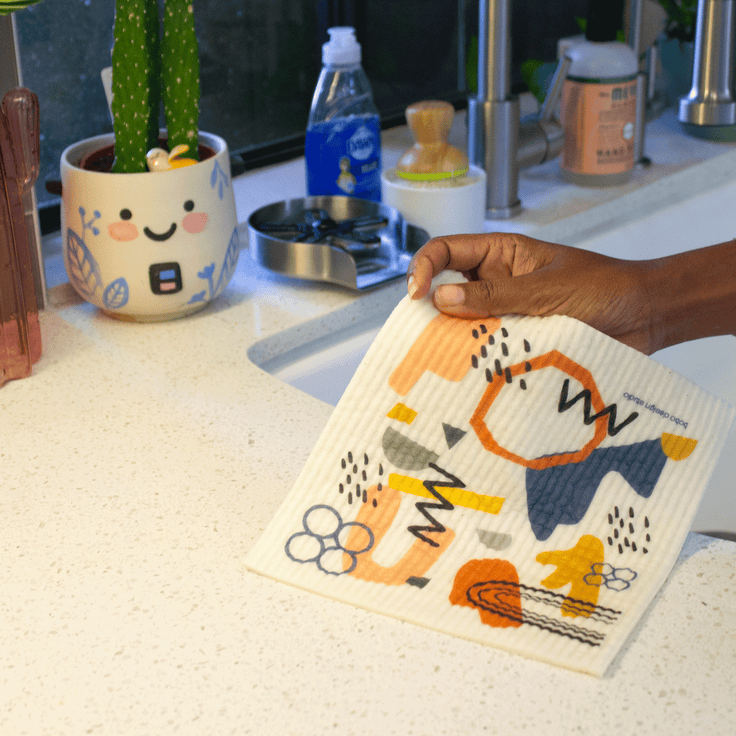 someone holding the mid mod super cloth in a kitchen next to a sink 