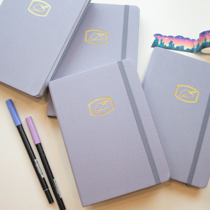 four cloud nine journals stacked on one another with two pens and a rolled out cloud cut southwest sunset washi tape 