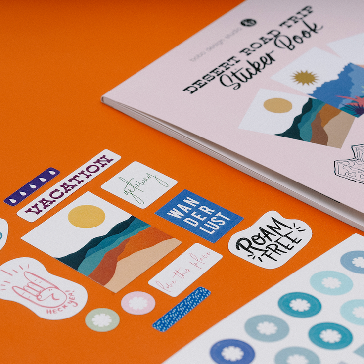 zoomed in image showing top part of desert road trip sticker book and to the left are twelve little stickers that come in the book 