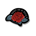 Image of the dont be a dick sticker that features a red rose. It is illustrated in the style of a tattoo
