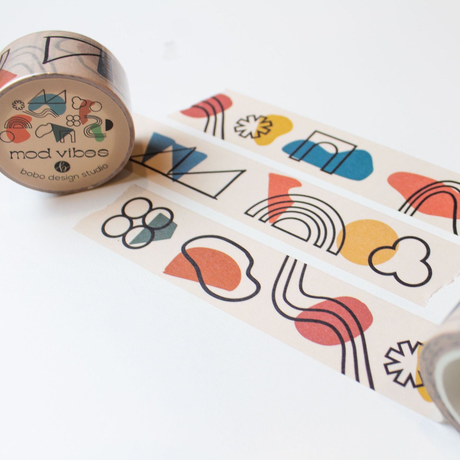 three mod vibes washi tape rolled out one inch wide with abstract lines and shapes on a light beige background