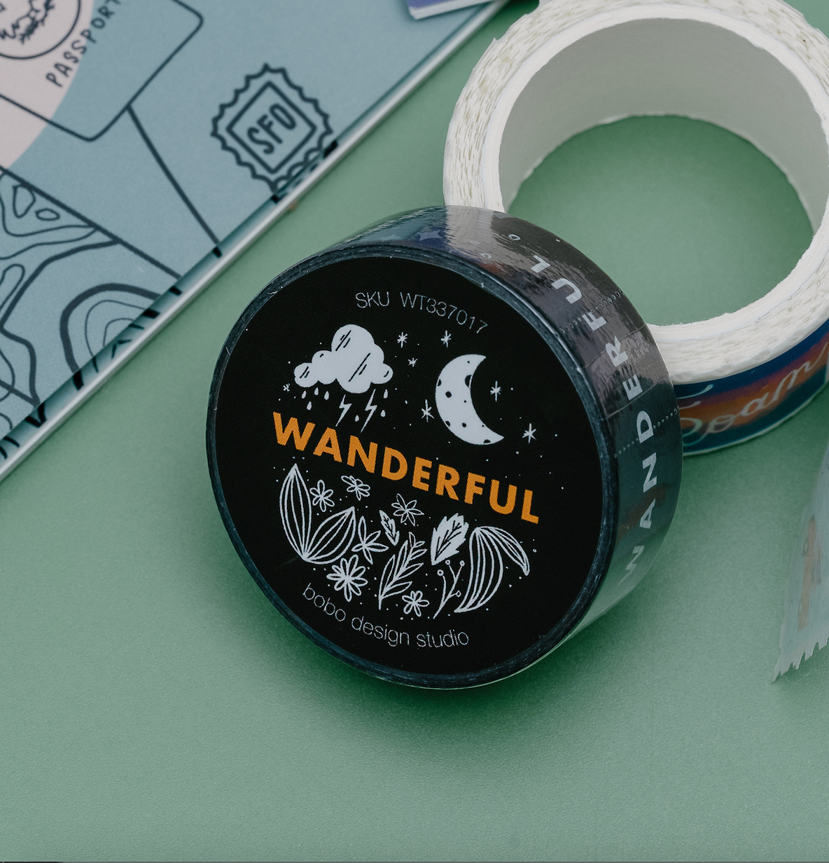 wanderful washi tape laying on another washi tape next to a wanderlust sticker book