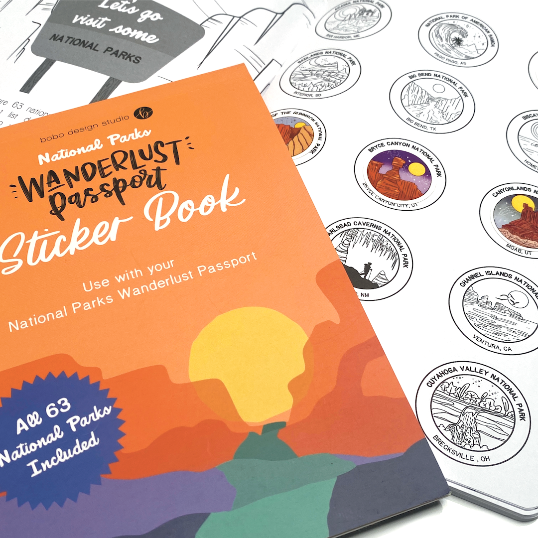 Wanderlust Passport National Parks Edition Journal and Stickerbook. The travel journal is opened to the National Park Tracker pages, and three circular National Park stickers from the Sticker book have been placed on their corresponding spot in the travel journal.