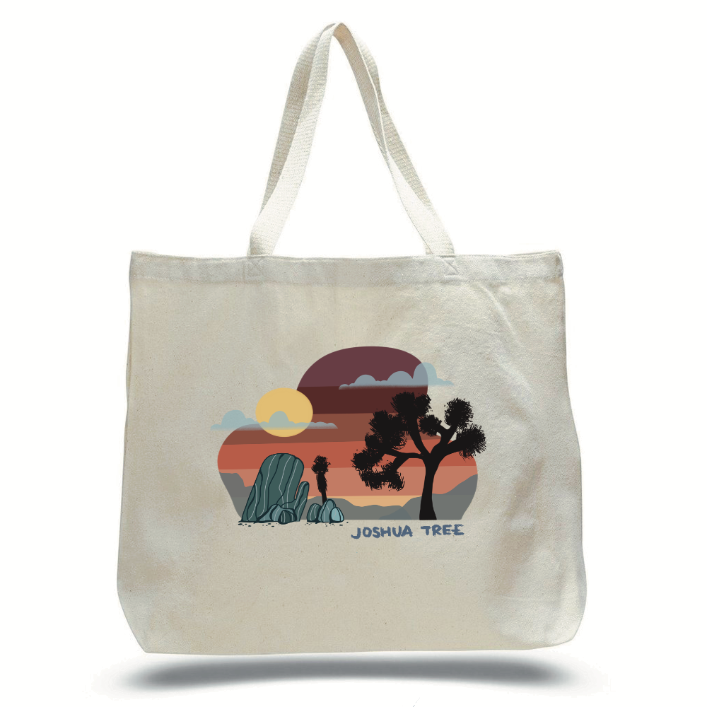 Large natural canvas colored tote bag with a spot illustration of a Joshua Tree landscape on the side. The printed image includes a sunset, sun, grey clouds, grey rocks, dark brown silhouetted Joshua trees over the words "JOSHUA TREE" in blue type.