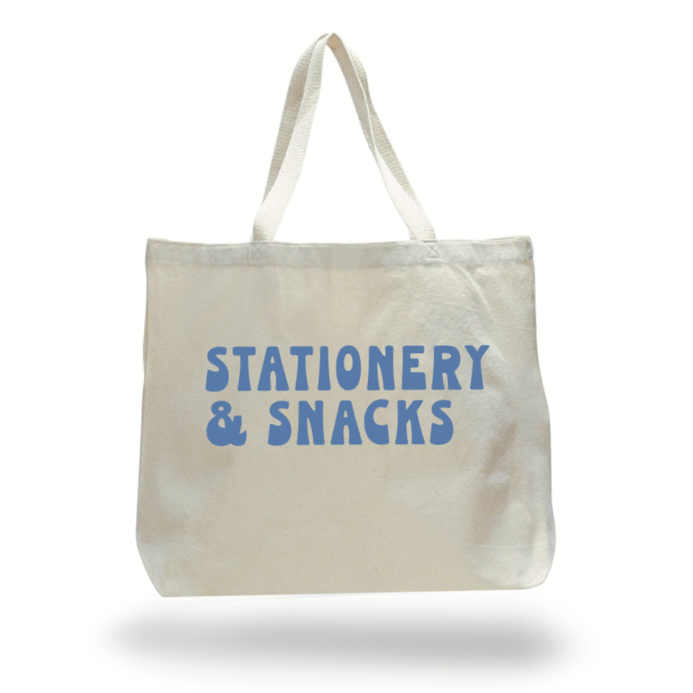 Large natural canvas colored tote bag with the words, stationery & snacks, in blue-lavender on the side.