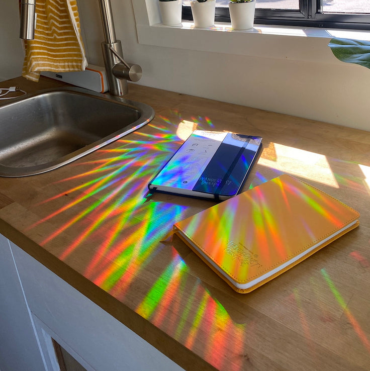 a sun catcher projecting onto two wanderlust passports on a counter 